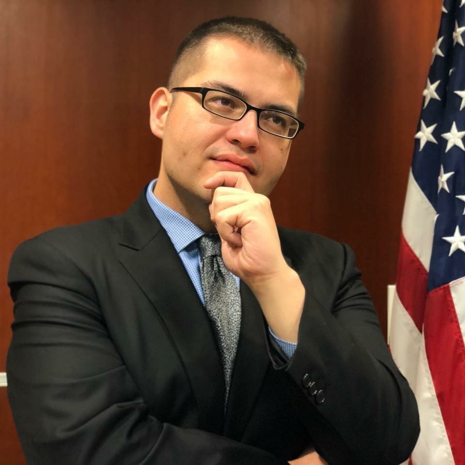 Sean Chao in a suit beside the American flag